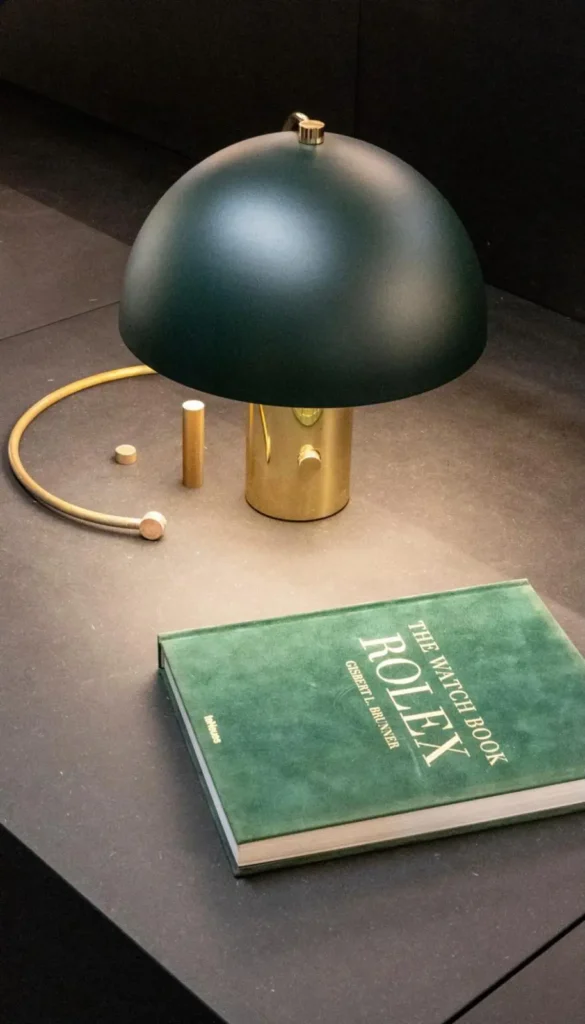 Carl lamp van Bankamp groene kap in metaal met een Rolex boek op de voorgrond
